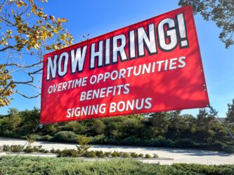 Red banner sign advertising for jobs available with sign on bonuses