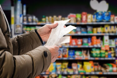 Minded man viewing receipts in supermarket and tracking prices